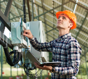 Factory worker wearing a flannel shirt and hard hat pushing a button on an electrical panel