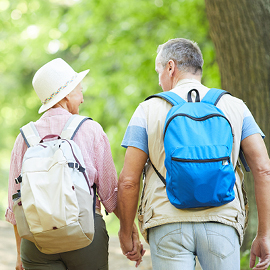 Older couple with back packs on going on an adventure in the woods