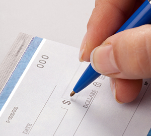 Person writing a check with a blue pen in his hand.